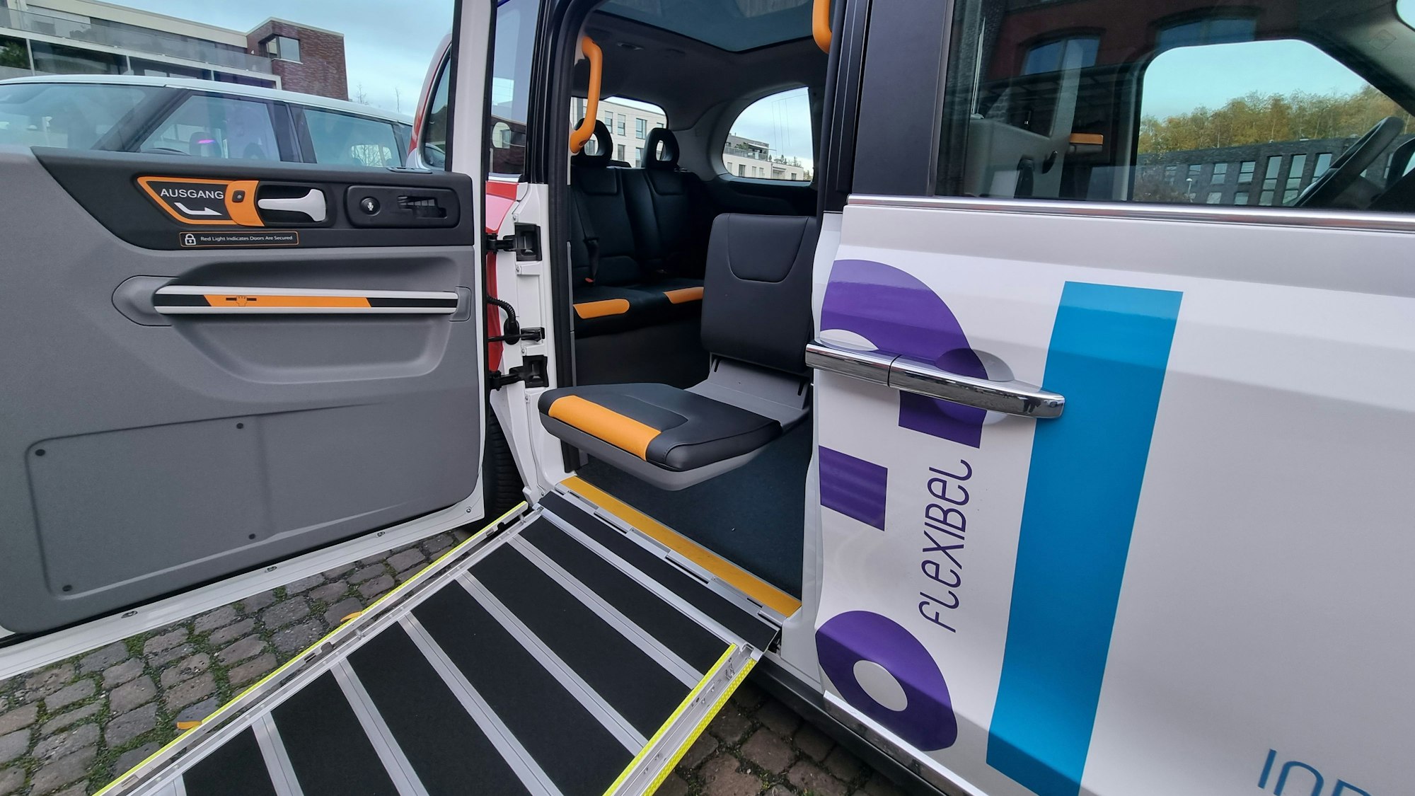 Blick in den Innenraum des Efi-Fahrzeugs. Eine Rollstuhlrampe ist ausgefahren, ein schwenkbarer Sitz zur Straße hin geneigt.