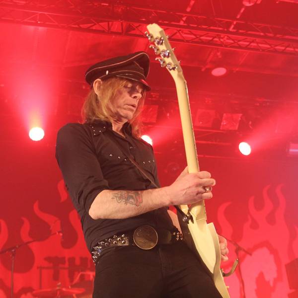 Der Hellacopters-Frontmann Nicke Andersson spielt auf der ganz in rotes Licht getauchten Bühne in Köln Gitarre.