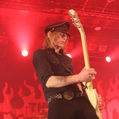 Der Hellacopters-Frontmann Nicke Andersson spielt auf der ganz in rotes Licht getauchten Bühne in Köln Gitarre.