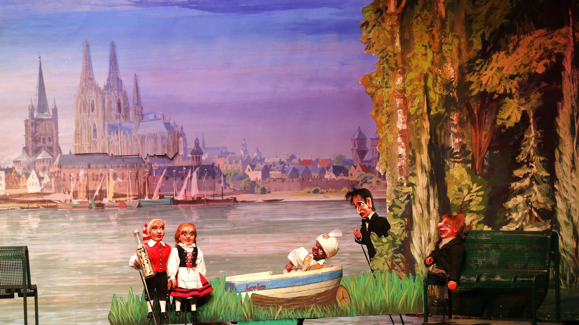 Das Hänneschen-Theater: Rechts Tünnes und Schäl. Im Hintergrund das damalige Kölner Panorama mit Dom, Groß St. Martin und Segelbooten auf dem Rhein.