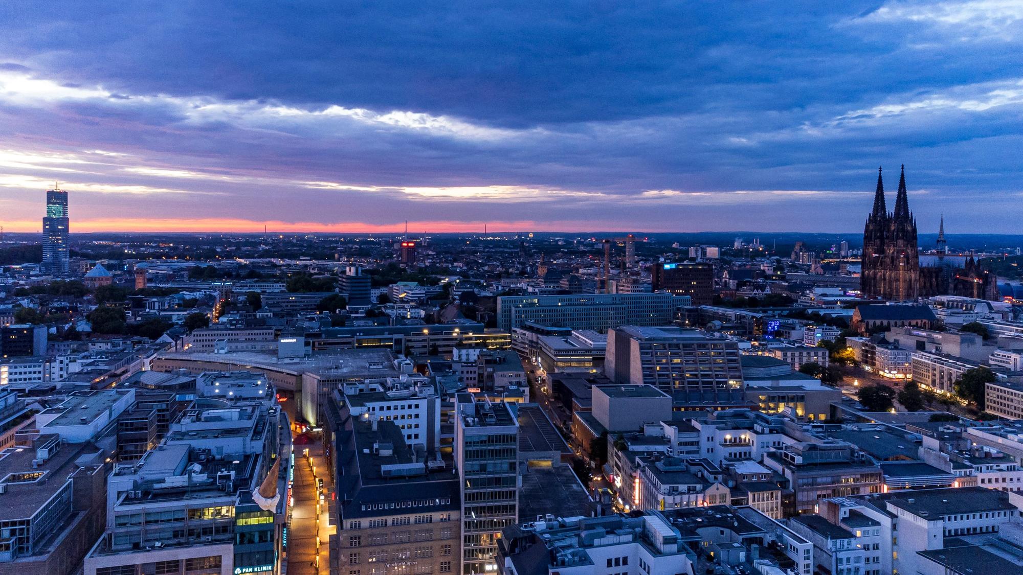 Ein Panoramabild der Stadt Köln bei dämmerndem Abendlicht.