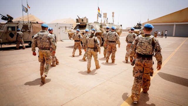 Soldaten der Bundeswehr marschieren im Camp Castor in Mali. Im Hintergrund sind Militärfahrzeuge zu sehen.