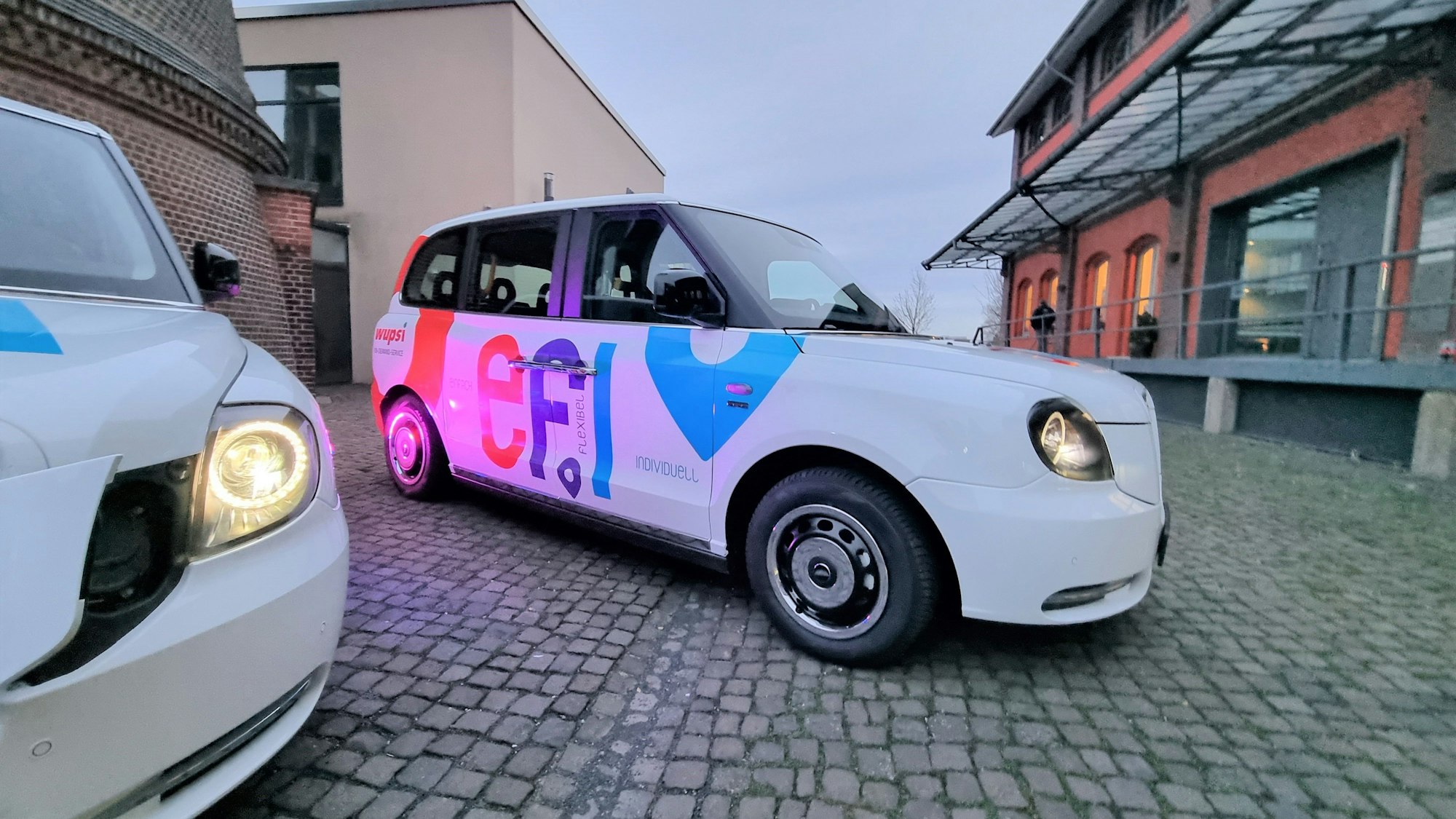 Ein Efi-Kleinbus mit Platz für sechs Fahrgäste steht auf dem Platz vor dem Funkenturm in Opladen.