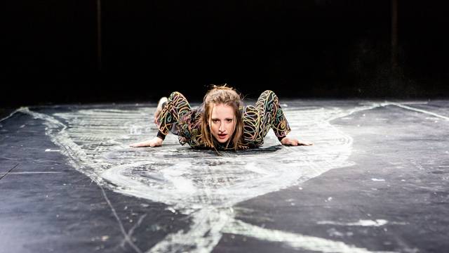 Die Schauspielerin Kristin Steffen liegt auf einem schwarzen Boden, der mit weißer Kreide bemalt ist.