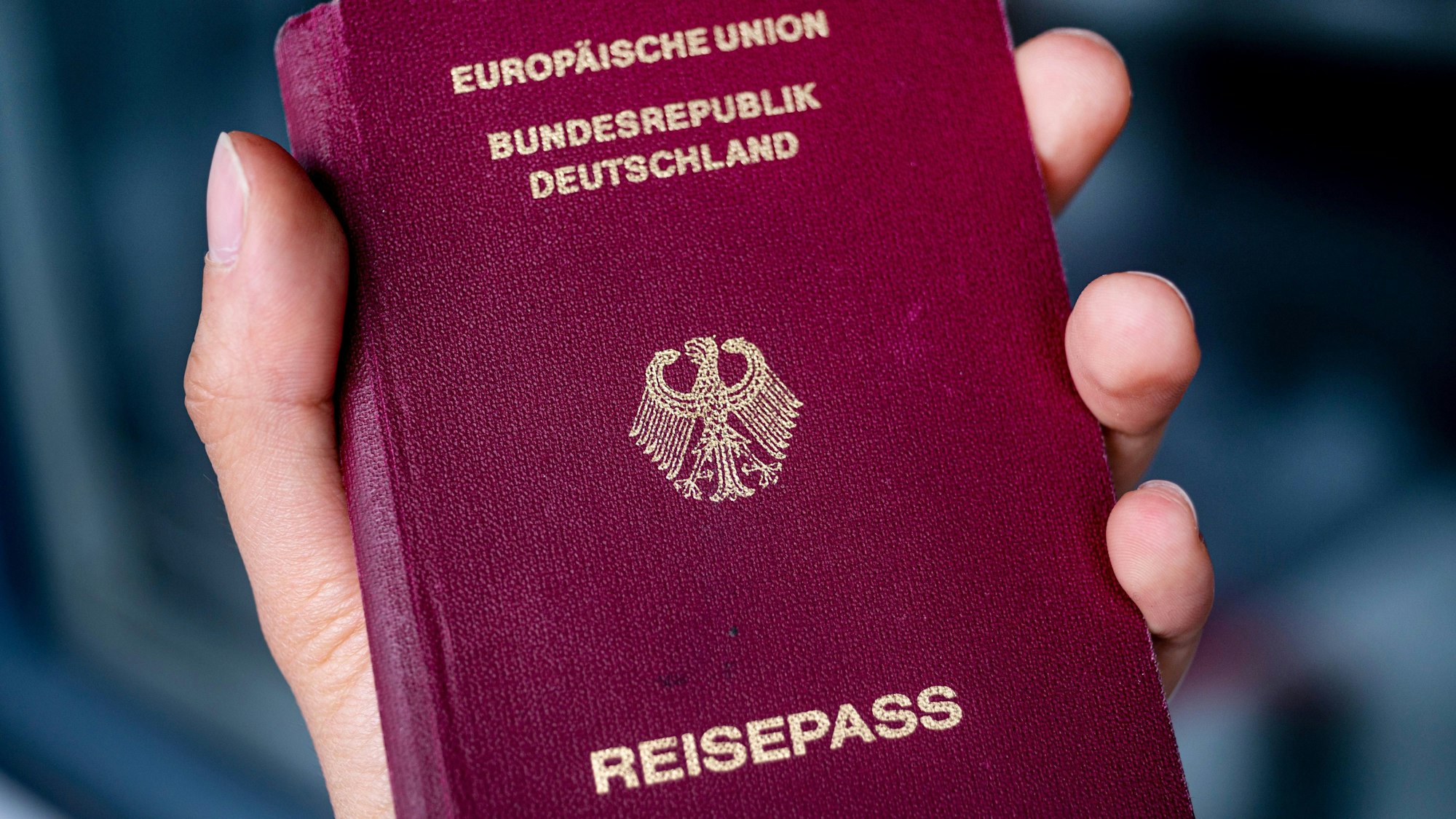 Eine Person hält in einer Hand einen deutschen Reisepass.