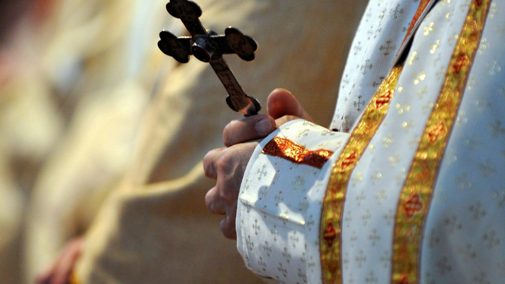 Ein Bischof hält während einer katholischen Messe ein Kreuz in den Händen.