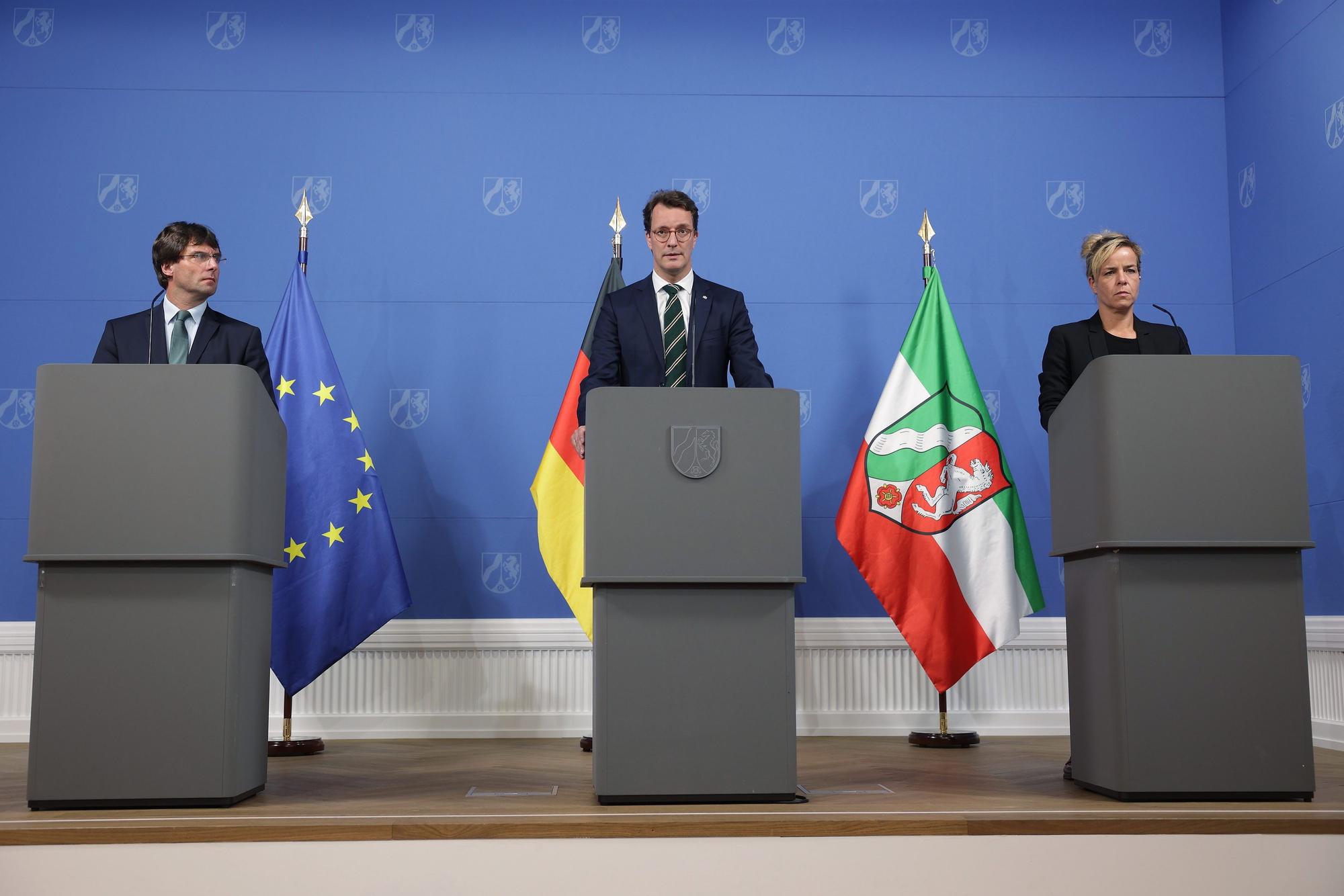 An Rednerpulten zu einer Pressekonferenz sind zu sehen: Marcus Optendrenk (l-r, CDU), Minister der Finanzen, Hendrik Wüst (CDU), Ministerpräsident Nordrhein-Westfalens, und Mona Neubaur (Bündnis 90/Die Grünen), Ministerin für Wirtschaft, Industrie, Klimaschutz und Energie