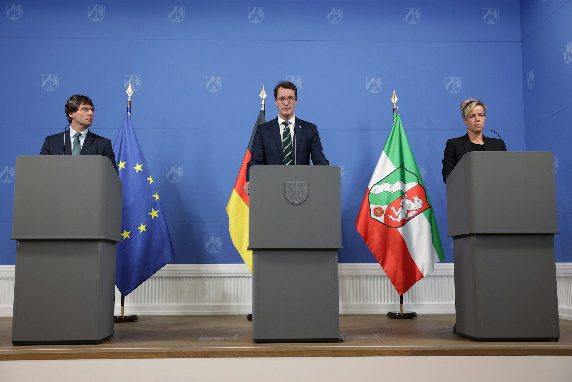 An Rednerpulten zu einer Pressekonferenz sind zu sehen: Marcus Optendrenk (l-r, CDU), Minister der Finanzen, Hendrik Wüst (CDU), Ministerpräsident Nordrhein-Westfalens, und Mona Neubaur (Bündnis 90/Die Grünen), Ministerin für Wirtschaft, Industrie, Klimaschutz und Energie