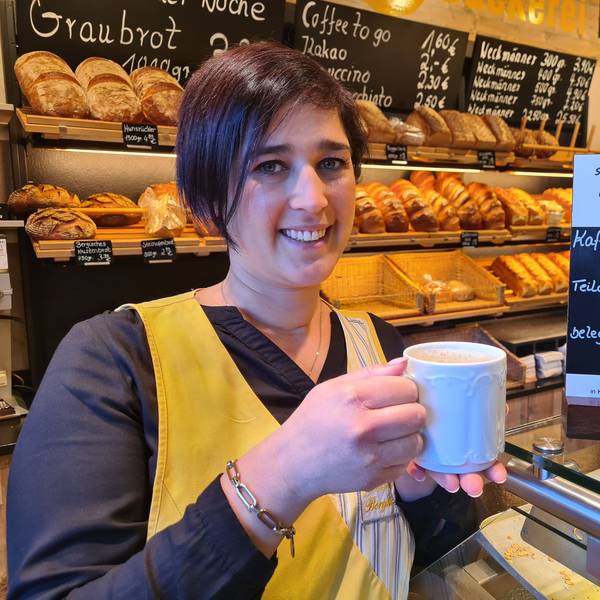 Jessica Küpper hält einen Kaffee in der Hand und steht vor dem Brotregal der Bäckerei Küpper in Bedburg.