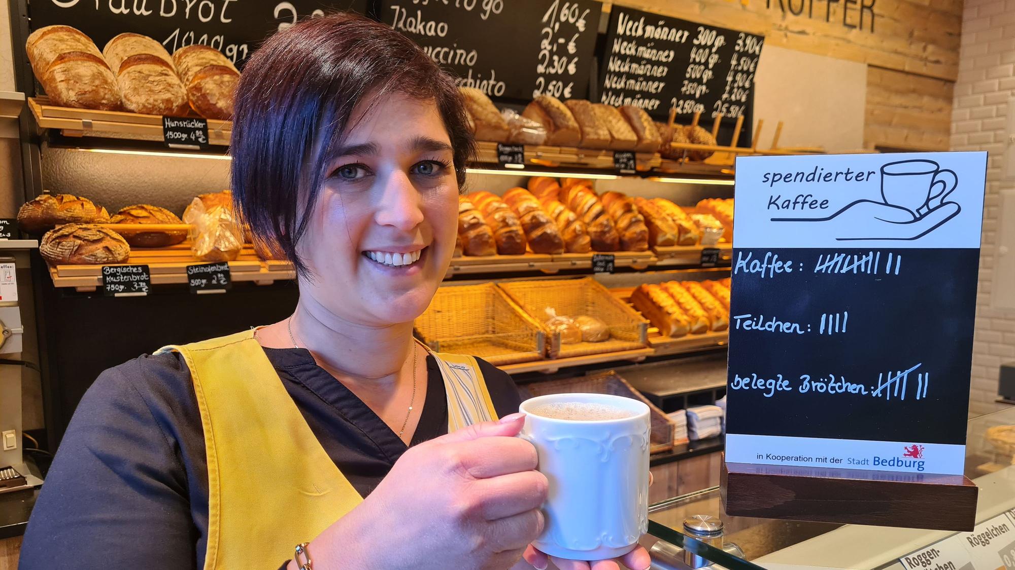 Jessica Küpper hält einen Kaffee in der Hand und steht vor dem Brotregal der Bäckerei Küpper in Bedburg.