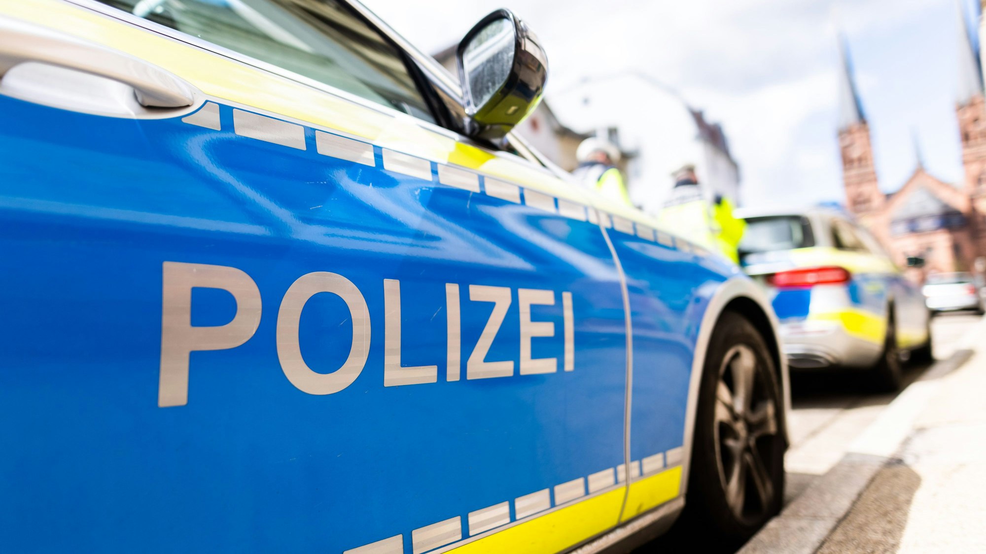 Zwei Einsatzfahrzeuge der Polizei stehen in Freiburg am Straßenrand.