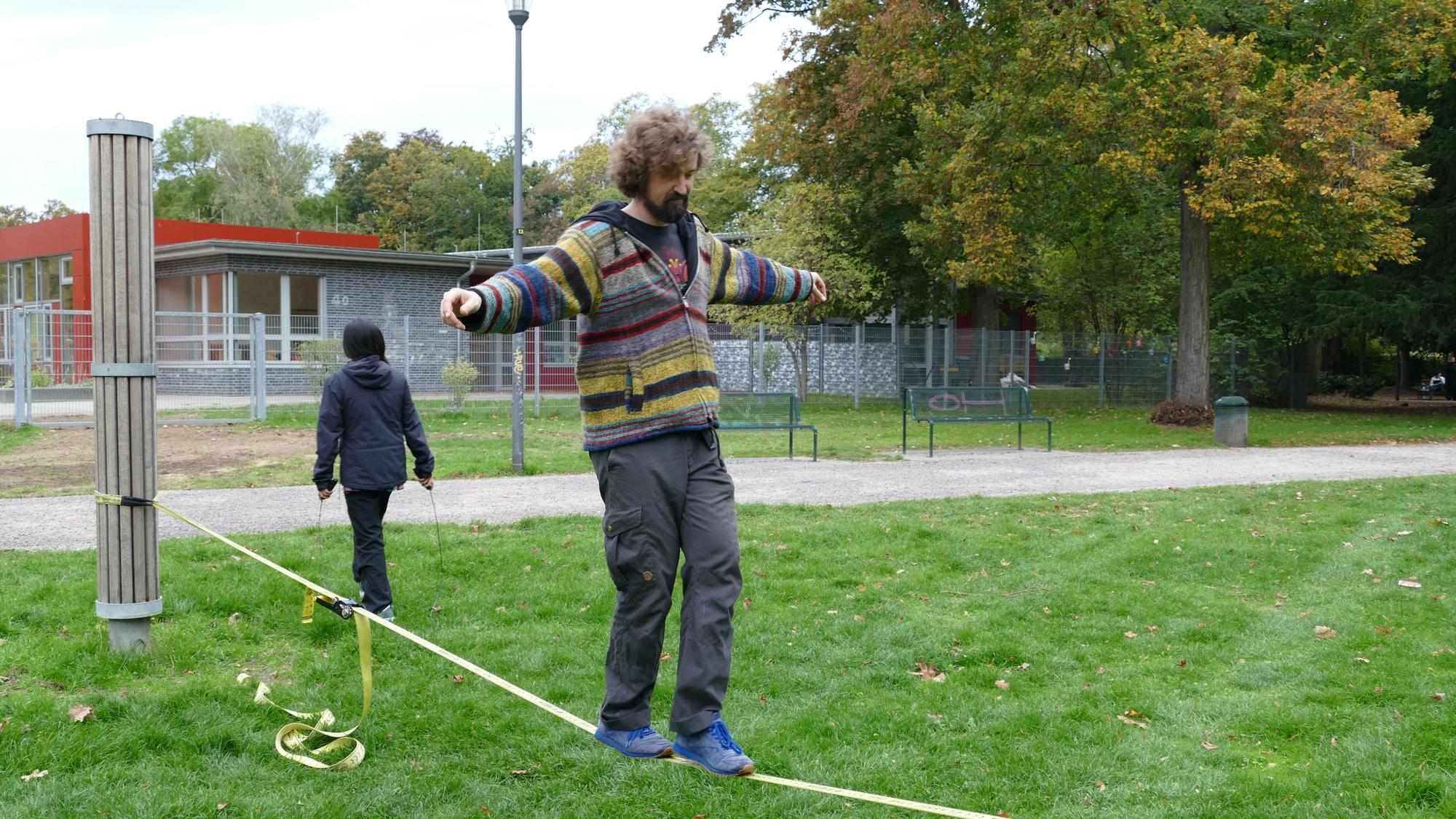 Ein Mann balanciert auf einer Slackline im Stadtgarten.