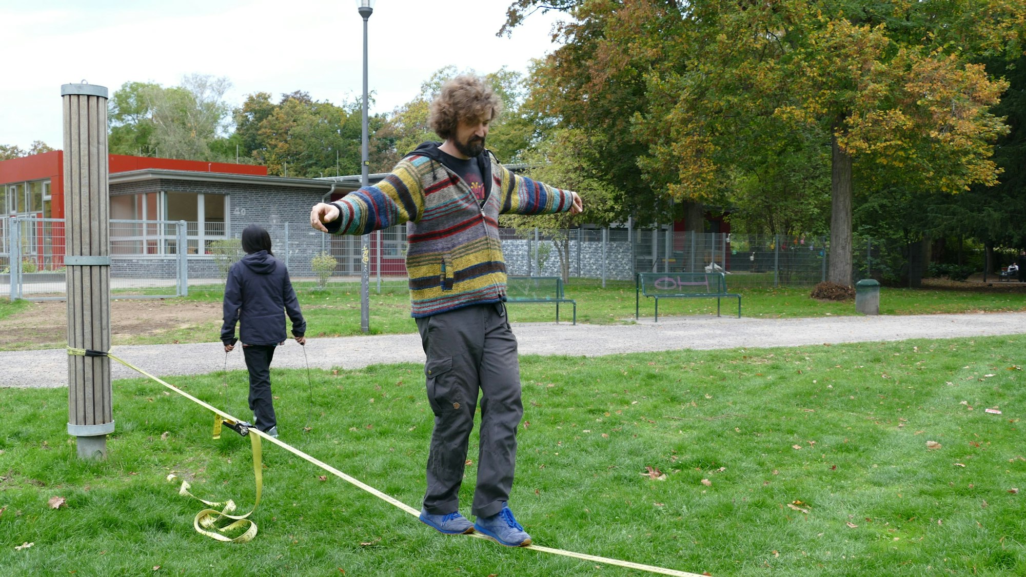 Ein Mann balanciert auf einer Slackline im Stadtgarten.