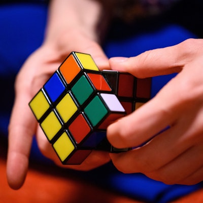 Eine junge Frau spielt mit einem Zauberwürfel.