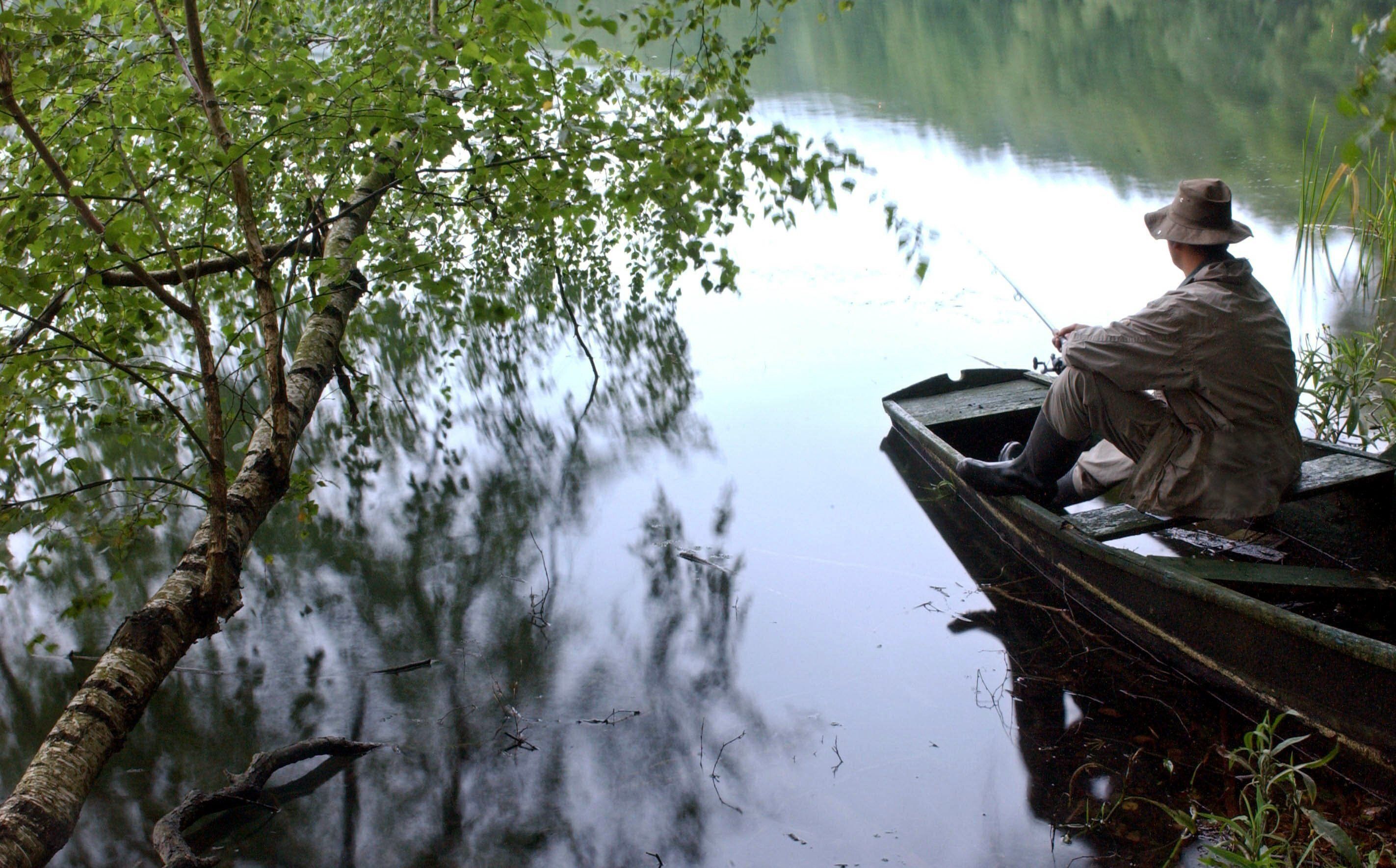 In einem ausgedienten Angelkahn am Ufer des Schervensees nahe Schernsdorf im Landkreis Oder-Spree (Brandenburg) sitzt in den frühen Morgenstunden ein Angler. (Symbolbild)