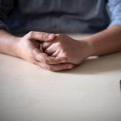 Ein Smartphone liegt vor einem jungen Mann auf dem Tisch.