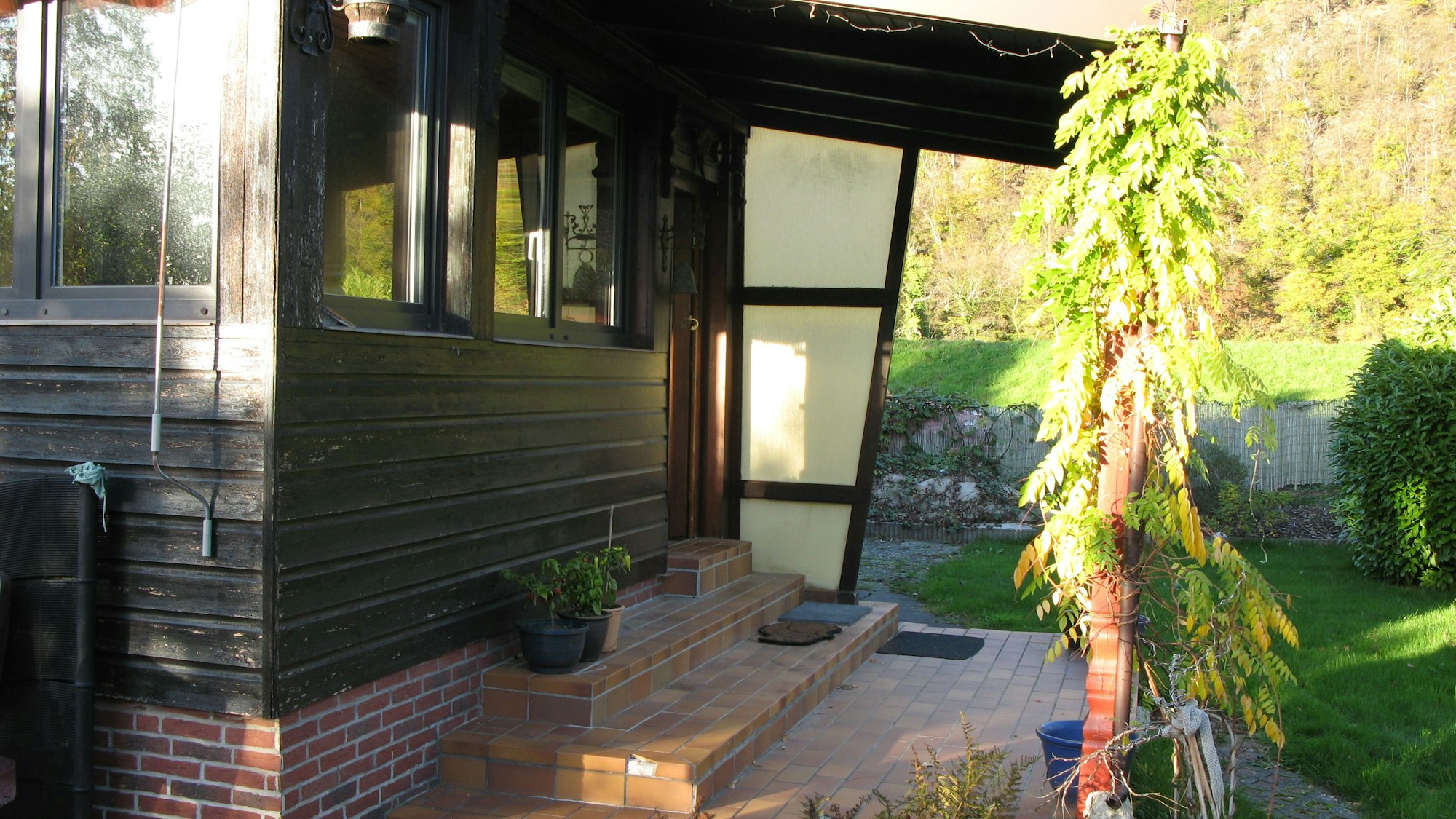 Am Eingang zum Bungalow gehen zwei Stufen hoch. Das Haus ist mit Holz verkleidet. Neben der Haustüre gibt es einen Windschutz und kleines Dach.