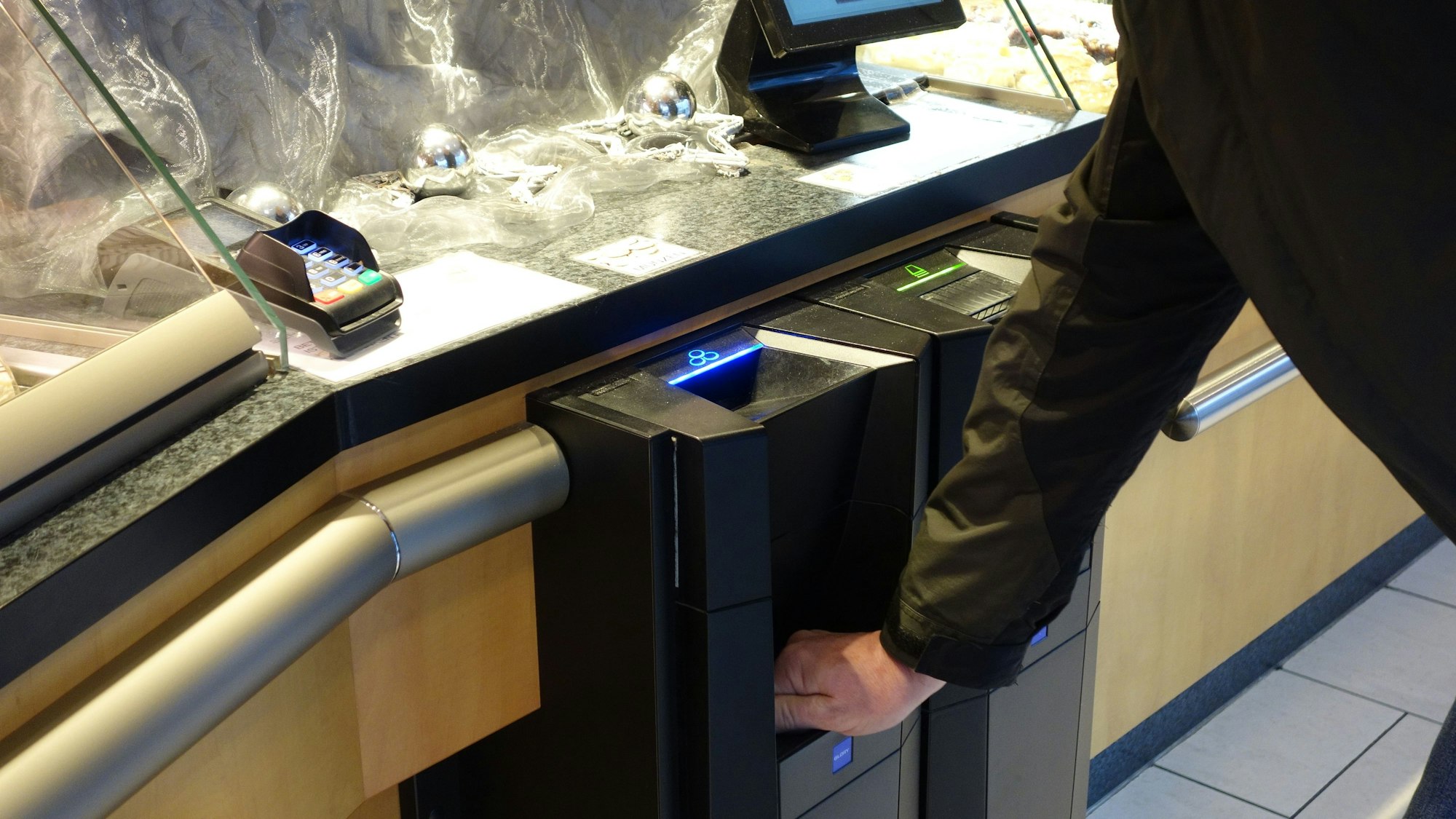 Ein Mann entnimmt von einem Einwurf-Kassensystem sein Rückgeld in der Bäckerei Willeke.