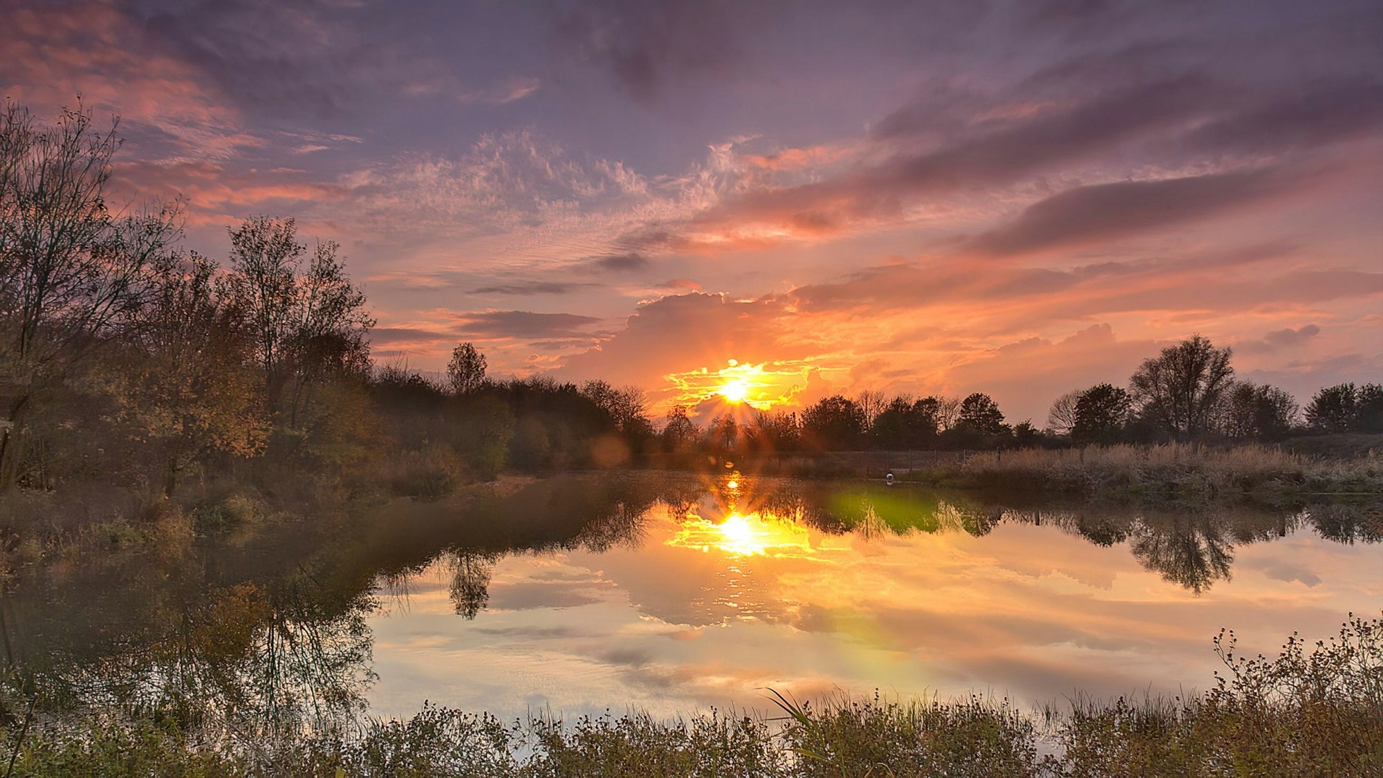 Über dem Teich geht die Sonne unter.
