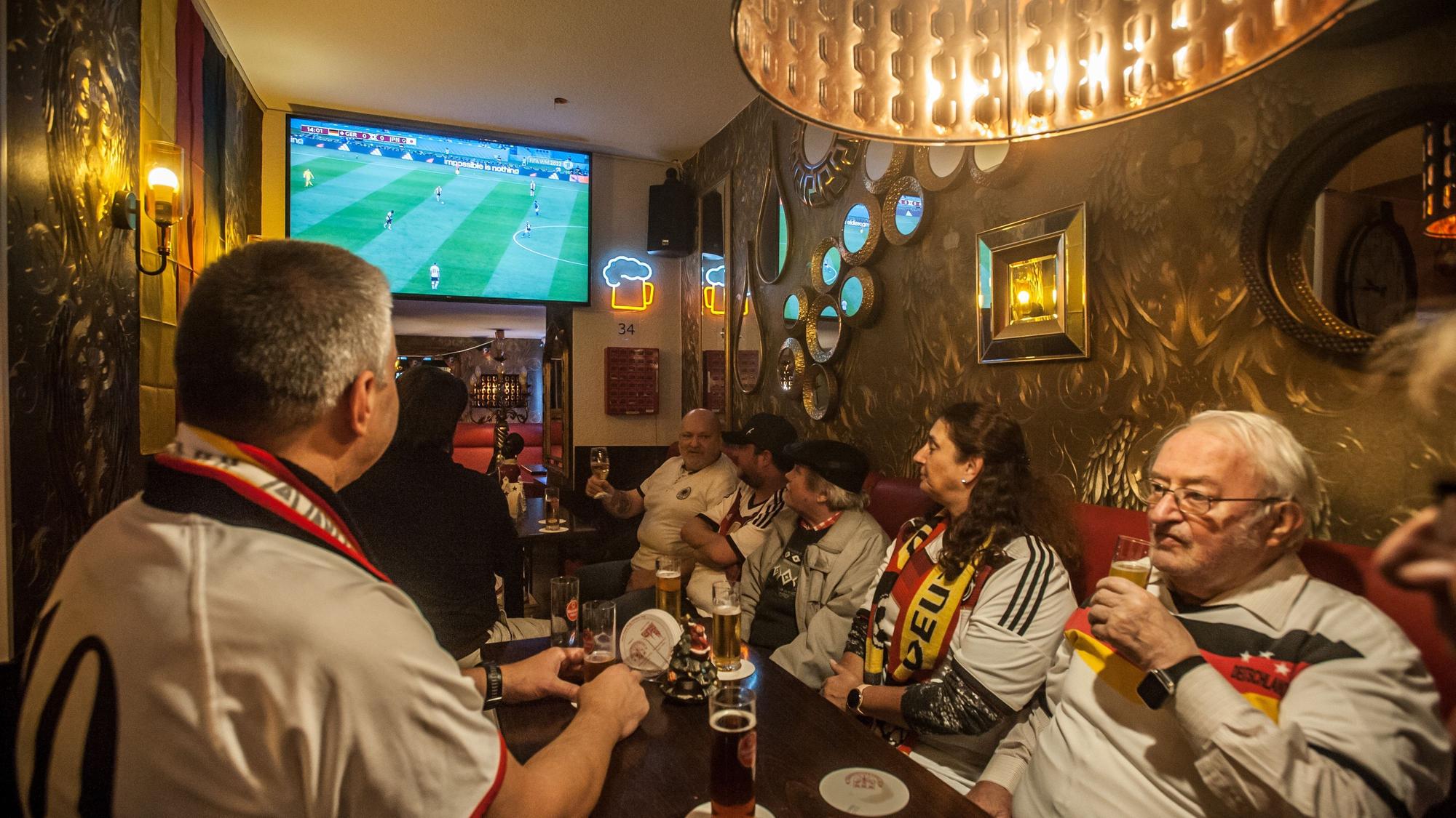 Blick in den Schankraum. Gut zehn Personen sitzen an Biertischen und trinken Kölsch. Sie tragen Trikots der deutschen Nationalmannschaft. Im Hintergrund läuft das Spiel auf einem Fernseher.