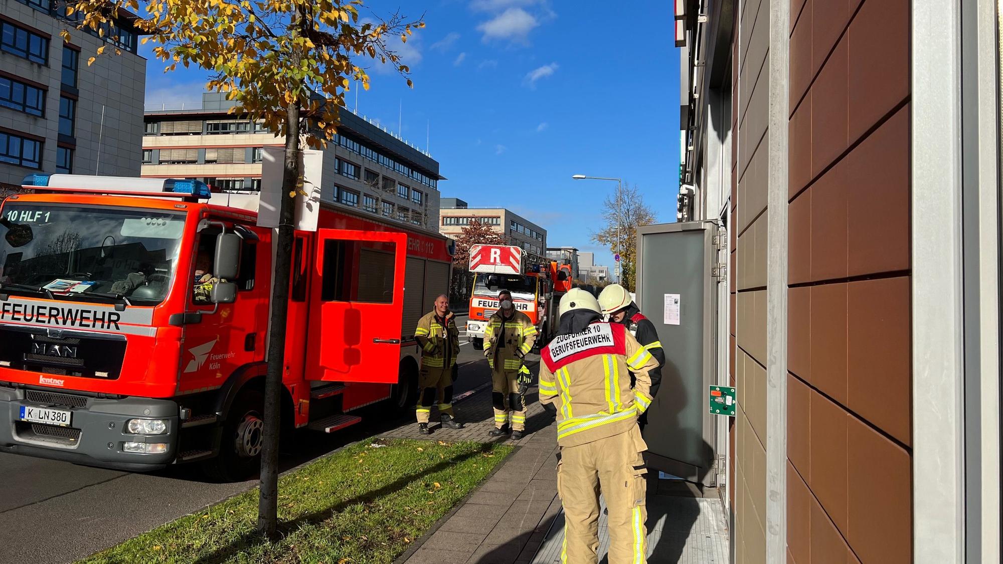 Mehrere Einsatzkräfte der Kölner Feuerwehr stehen vor den Köln Arcaden in Kalk.