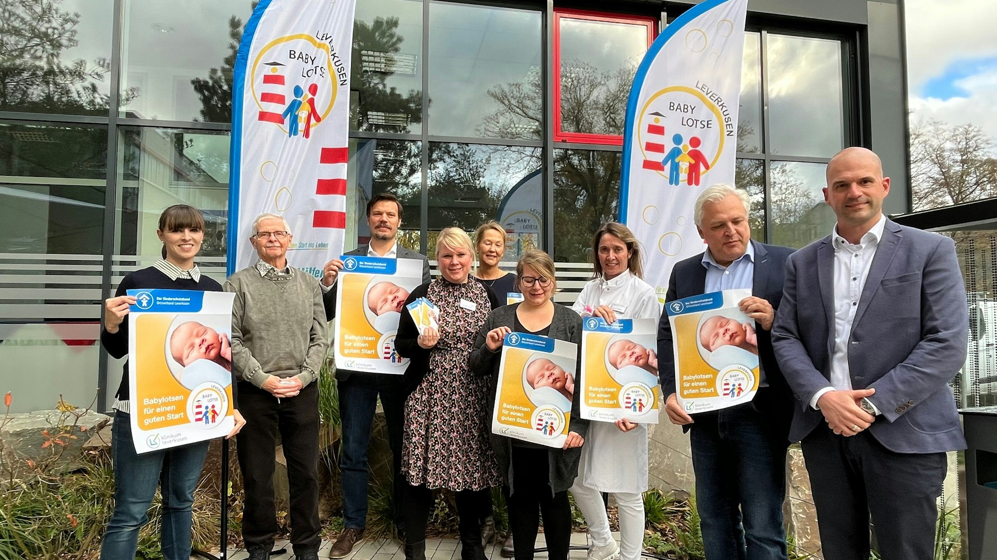 Mitarbeiterinnen und Mitarbeiter des Klinikums sowie Vertreter von Stadt und Kinderschutzbund stehen mit Plakaten zum Projekt Babylotsen vor dem Klinikum.