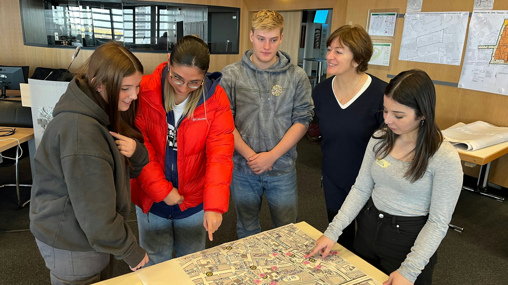 Britta Demmer mit vier Jugendlichen an einer Karte mit Markierungen.
