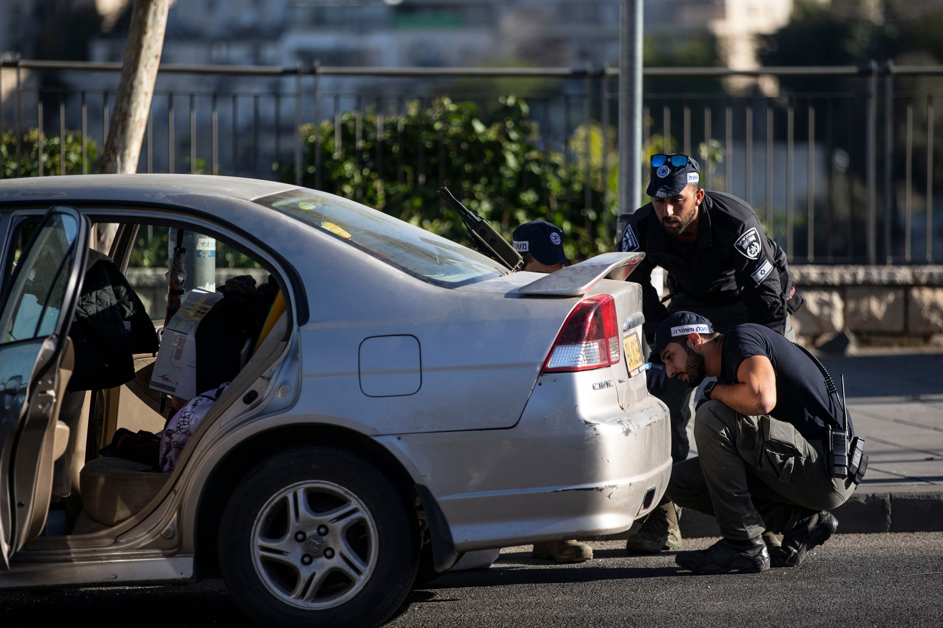 Zwei Polizisten in Jerusalem untersuchen ein silbernes Auto nahe der Bushaltestelle, wo sich die Explosionen ereigneten.
