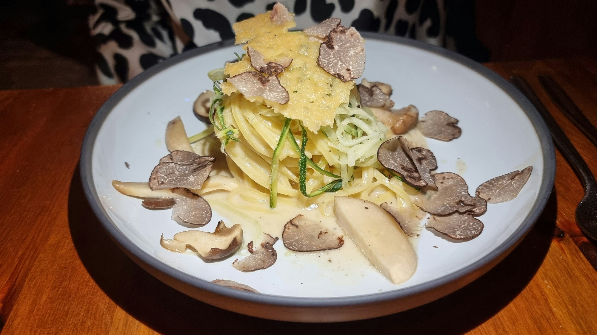 Angerichteter Teller Tagliarini mit italienischem Trüffel, Kräutersaitlingen und Zucchinistreifen.