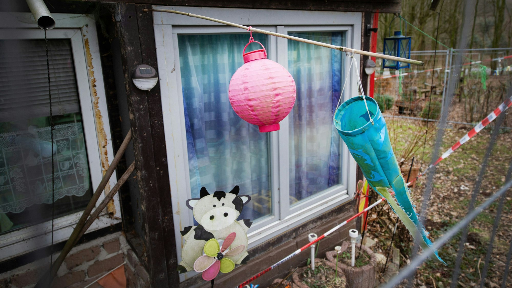 Hinter einem Zaun und Polizeiabsperrband ist ein Lampion und ein Windspiel auf dem Campingplatz Eichwald zu sehen. Der Untersuchungsausschuss des Düsseldorfer Landtags zum sexuellen Kindesmissbrauch in Lügde setzt am Freitag seine Zeugenvernehmungen fort.