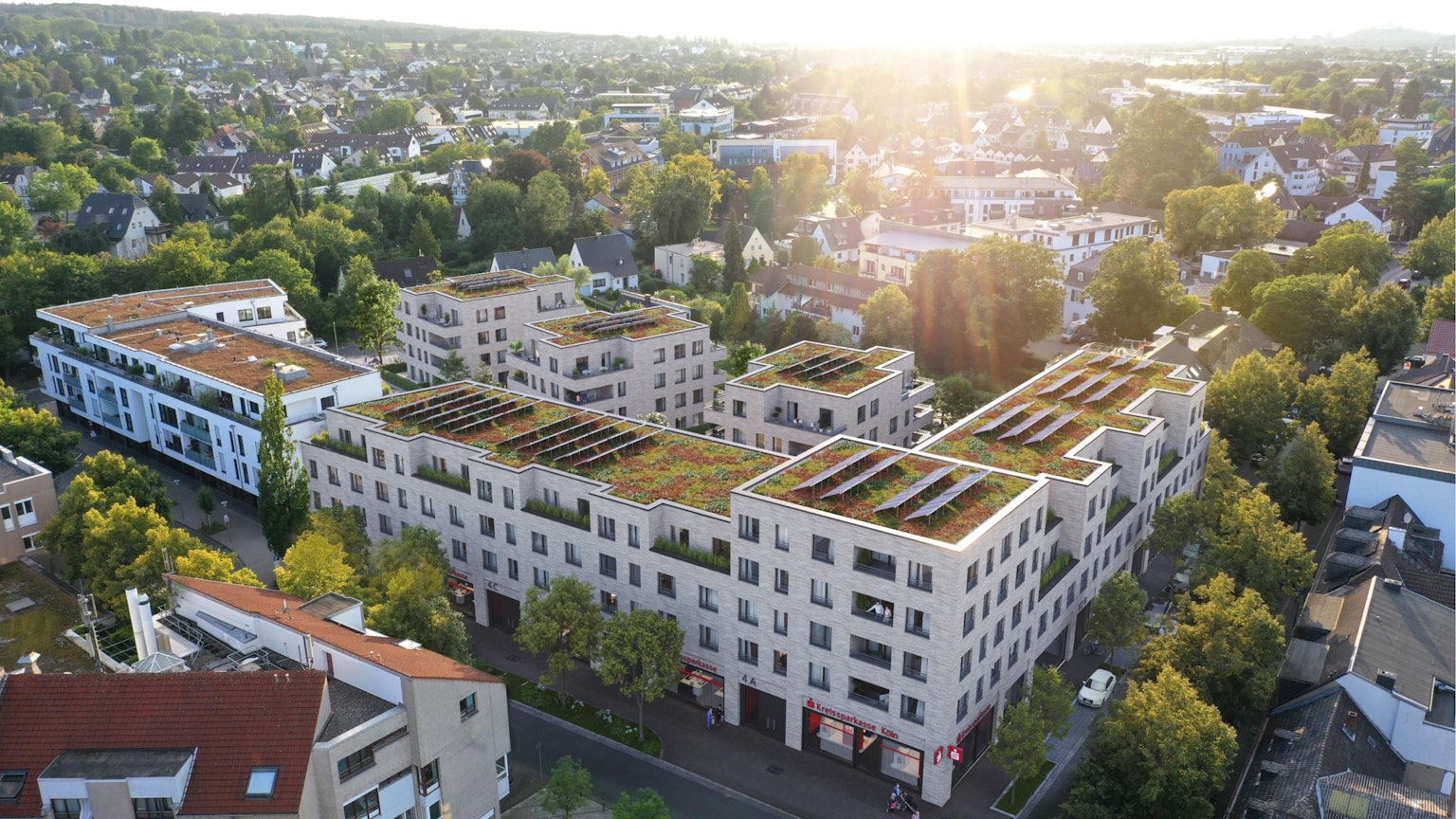 Die Visualisierung zeigt einen neuen Gebäudekomplex mit grünen Dächern und Solarpaneelen.