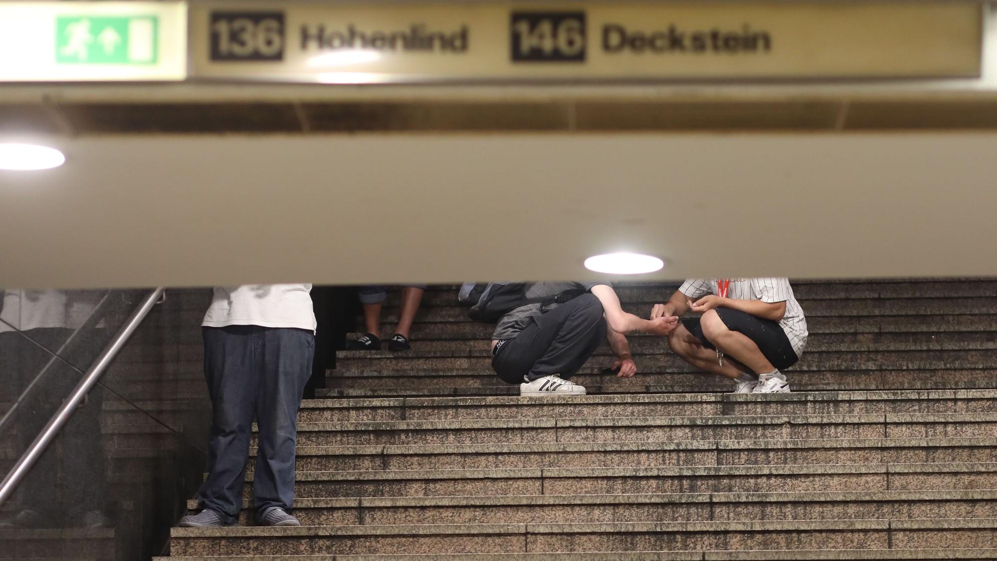 Auf der Treppe zur U-Bahn am Neumarkt wickeln ein Dealer und ein Konsument ein Drogengeschäft ab.