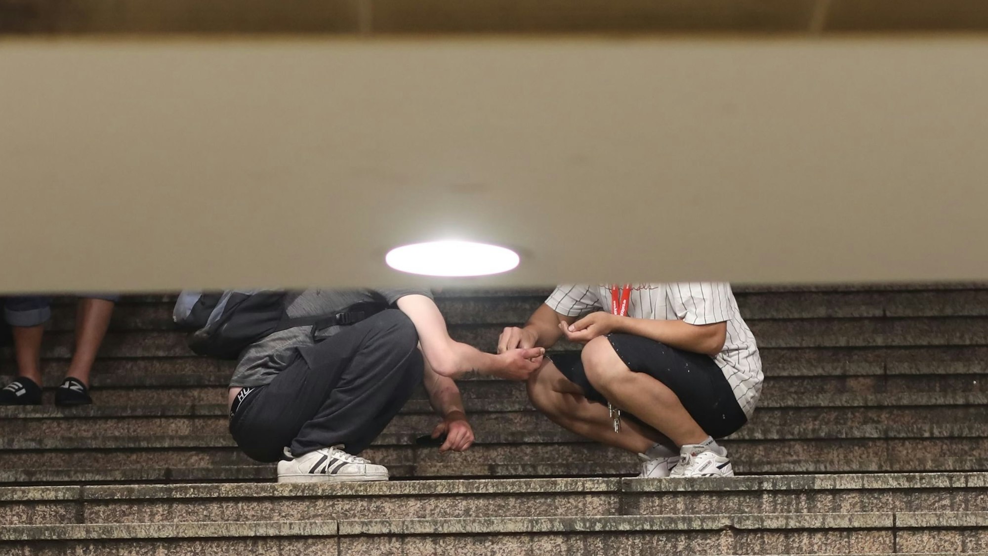 An der HUGO Passage am Neumarkt, Dealer und Konsumenten treffen aufeinander. Zwei Passanten auf der Treppe zur U-Bahn. Hier findet gerade ein Geschäft statt.