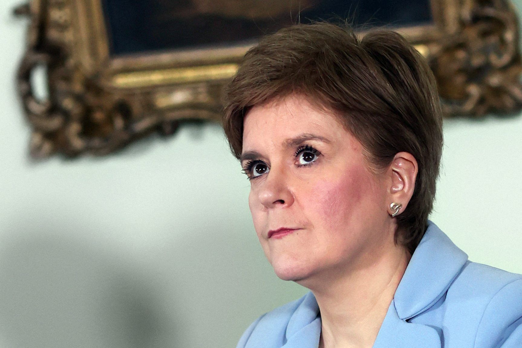 Nicola Sturgeon, Ministerpräsidentin von Schottland steht vor einem goldenen Bilderrahmen und schaut nach oben.