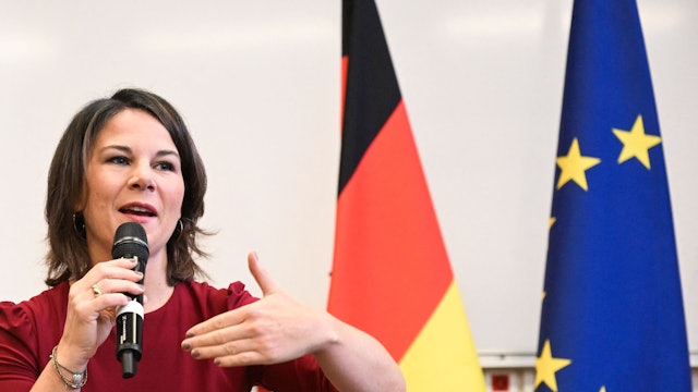 Annalena Baerbock spricht auf einer Konferenz. Im Hintergrund sind eine Europa- und eine Deutschlandflagge.