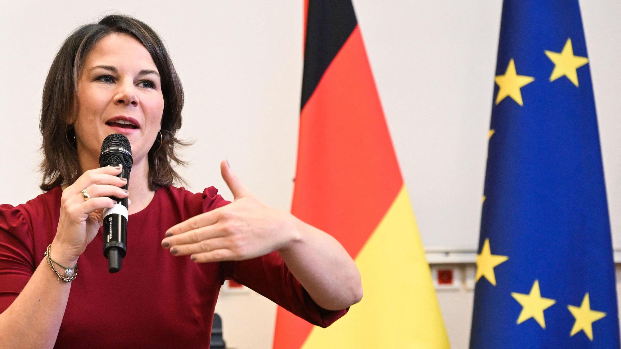 Annalena Baerbock spricht auf einer Konferenz. Im Hintergrund sind eine Europa- und eine Deutschlandflagge.
