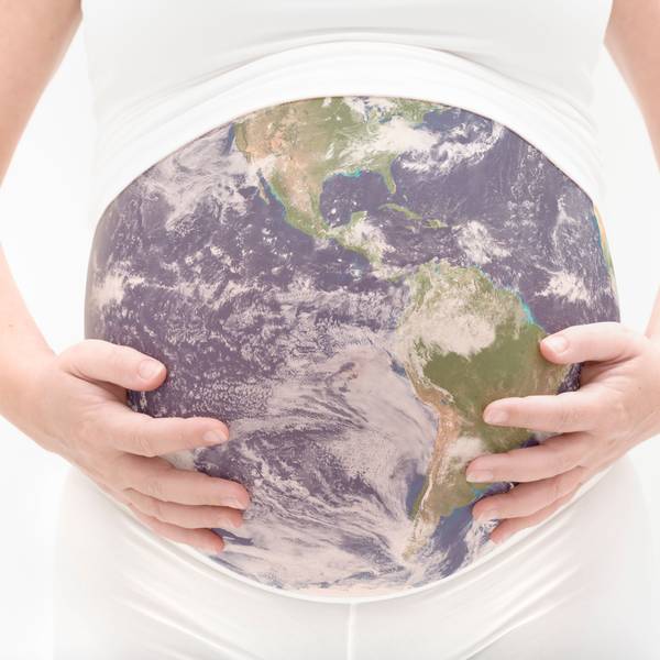 Eine schwangere Frau hält ihren Bauch, der aussieht wie die Erdkugel.