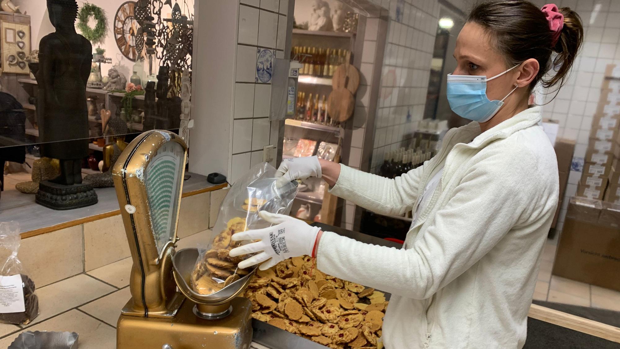 Eine Mitarbeiterin verpackt Kekse per Hand in durchsichtige Plastiktüten.