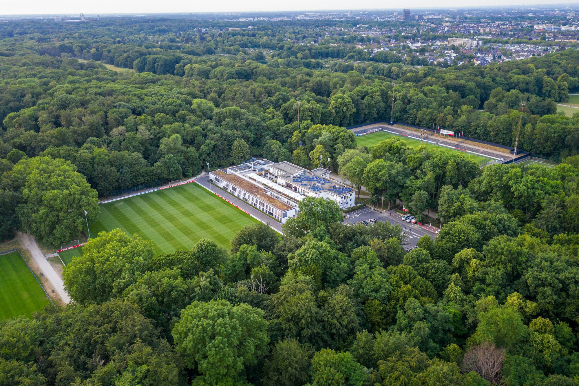 Das Bild zeigt das Geißbockheim mit dem Trainingsplatz 1 (links) und dem Franz-Kremer-Stadion (rechts) im Äußeren Grüngürtel.