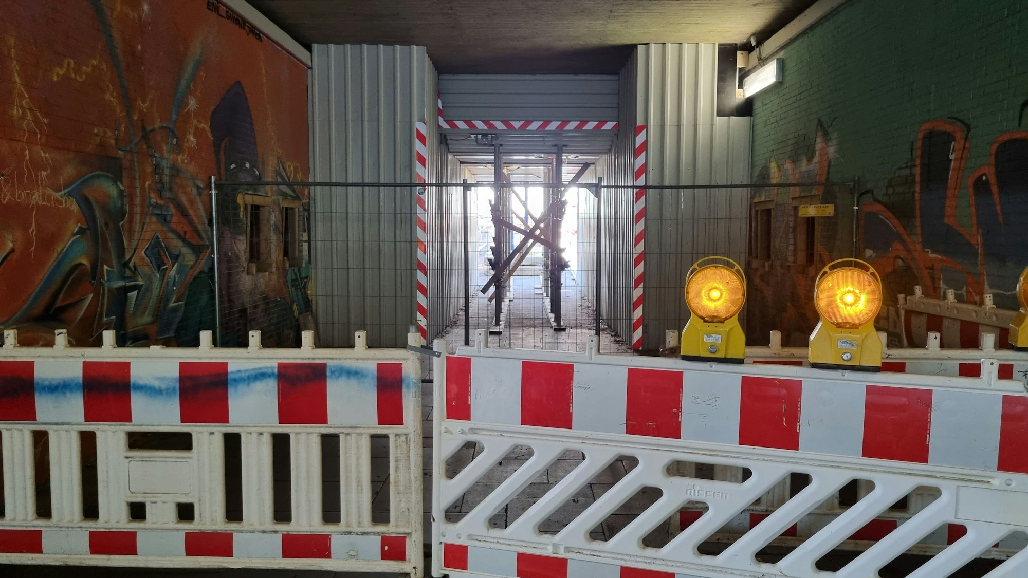 Blick in die Fußgängerunterführung zwischen Stadtpark und Innenstadt. Davor stehen Bauzäune, im Hintergrund sind Gerüstarbeiten zu erkennen.