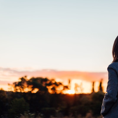 Frau von hinten blickt in einen Sonnenuntergang Foto: Getty Images / Oscar Wong