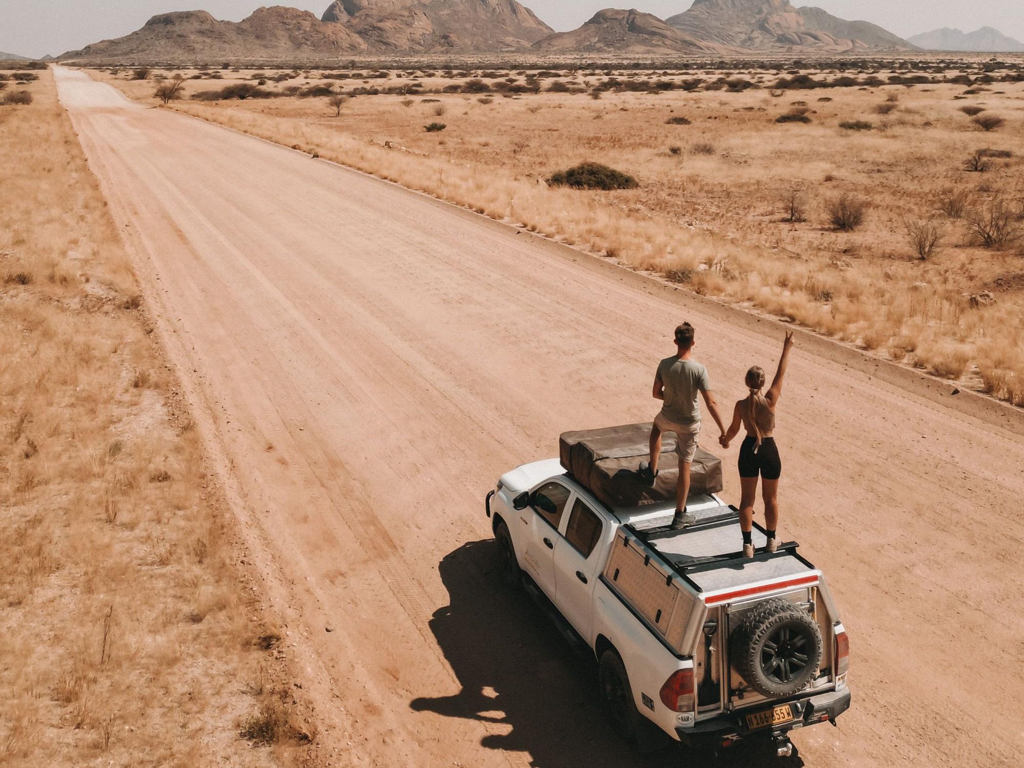 Die Kölnerin und Instagram-Reisebloggerin Jil Eileen Füngeling steht mit ihrem Freund Jaimy van Rumpt auf einem Autodach.