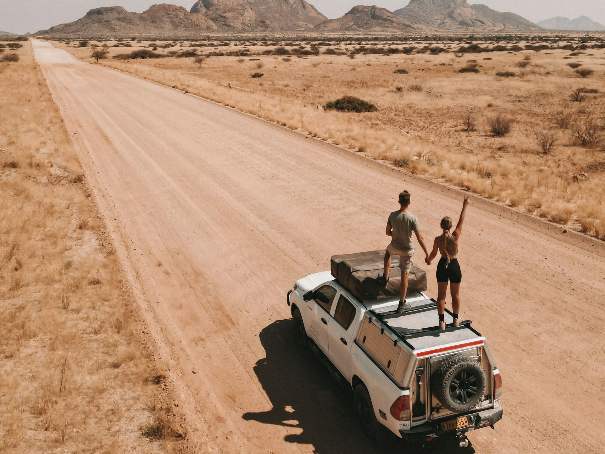 Die Kölnerin und Instagram-Reisebloggerin Jil Eileen Füngeling steht mit ihrem Freund Jaimy van Rumpt auf einem Autodach.