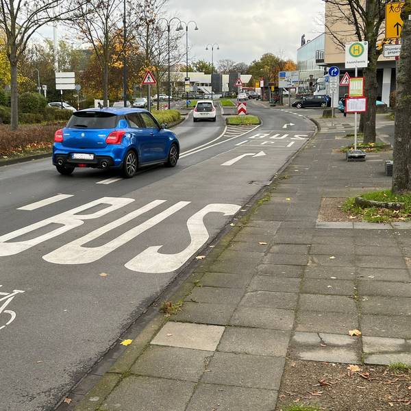 Ein Auto biegt auf eine Fahrspur, die für Busse und Fahrräder gekennzeichnet ist.