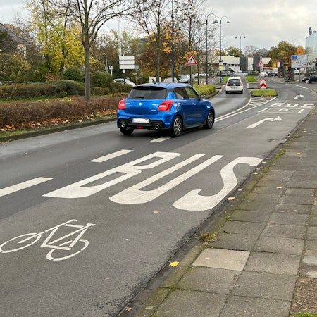 Ein Auto biegt auf eine Fahrspur, die für Busse und Fahrräder gekennzeichnet ist.