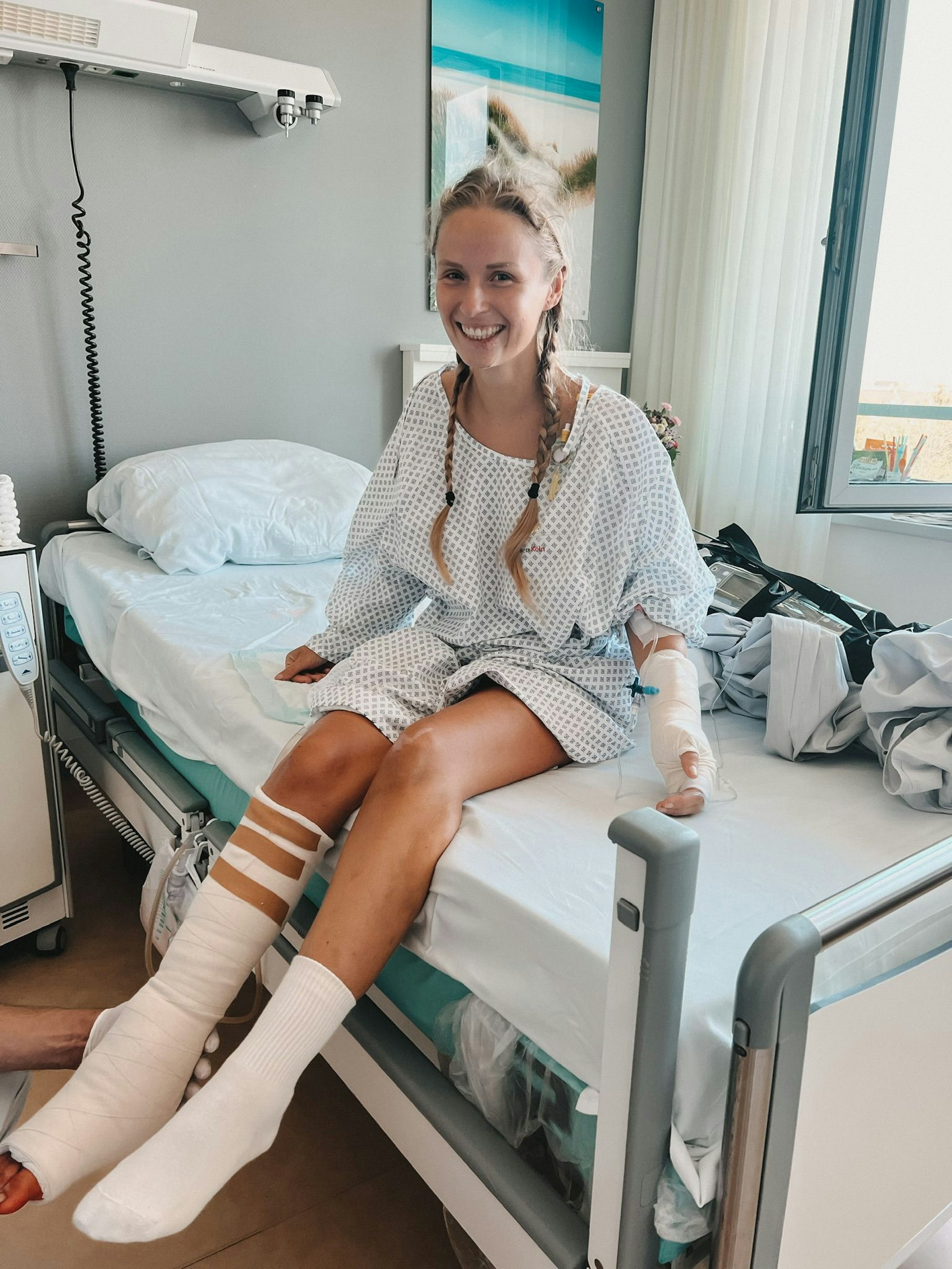 Die Kölnerin und Instagram-Reisebloggerin Jil Eileen Füngeling sitzt auf einem Bett im Krankenhaus.