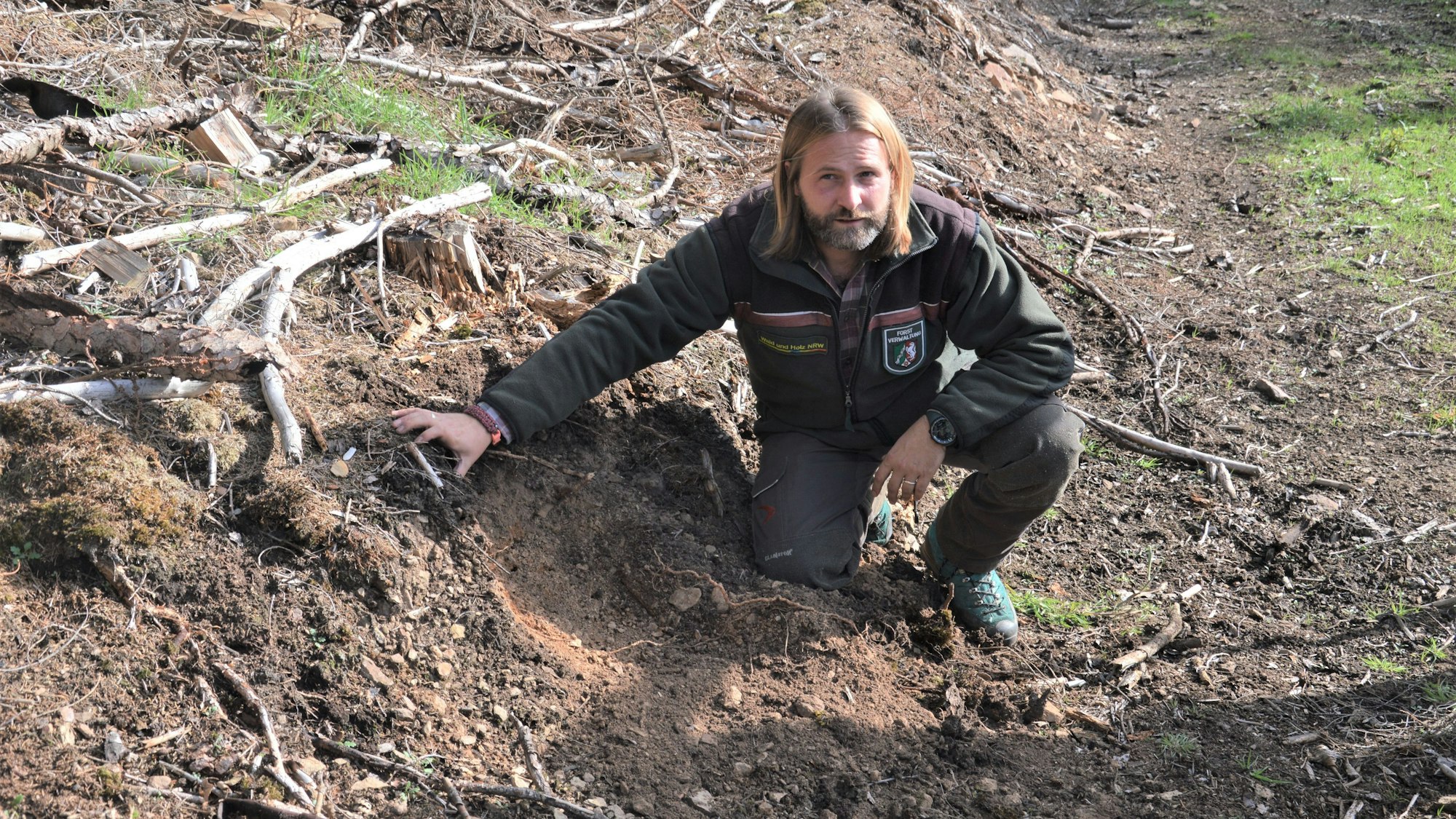 Wolfsberater und Revierförster Markus Wunsch vom Regionalforstamt Hocheifel-Zülpicher Börde hockt auf dem Boden.