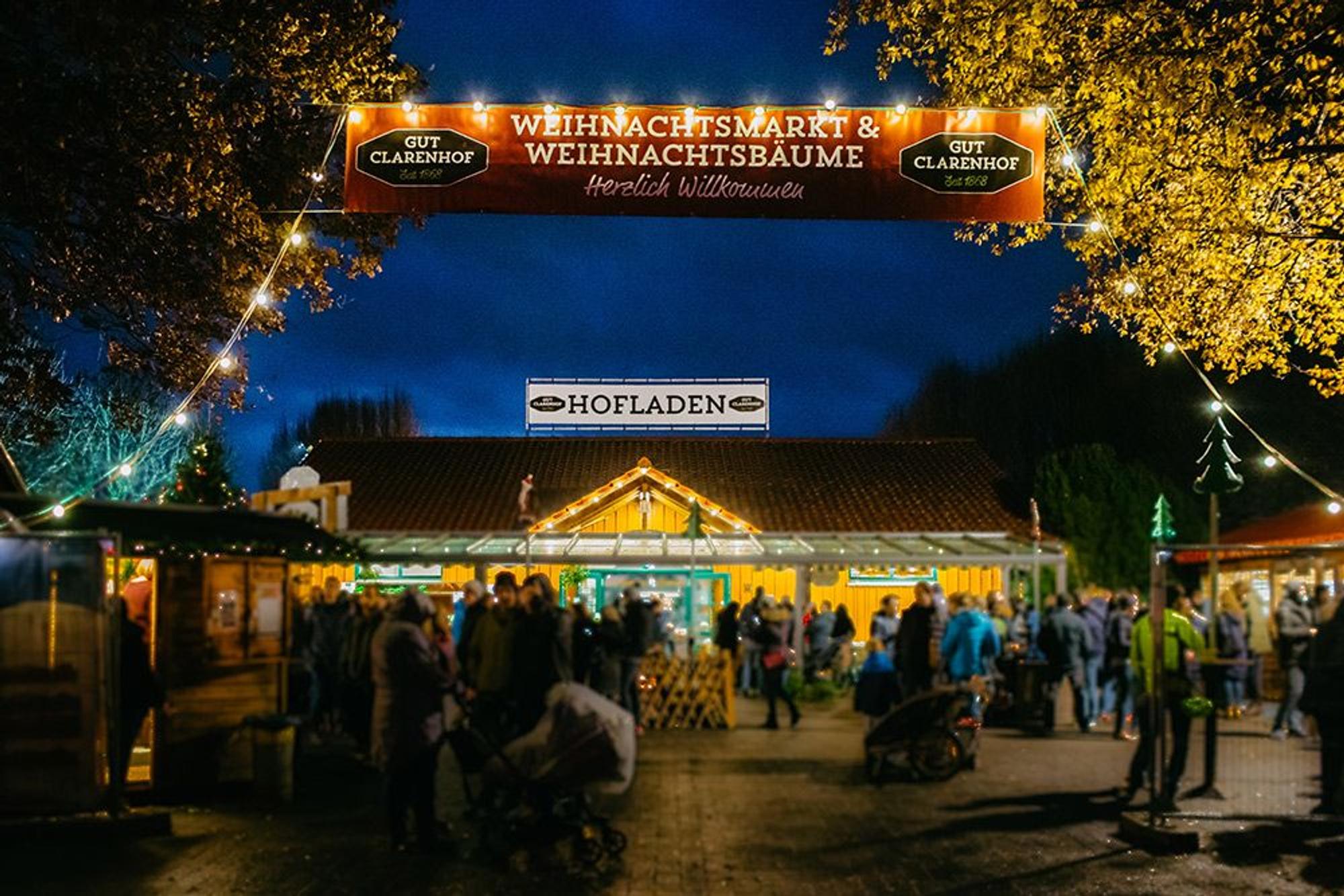 Beleuchteter Hofladen und Weihnachtsmarkt auf dem Gut Clarenhof in Köln Frechen bei Dunkelheit.
