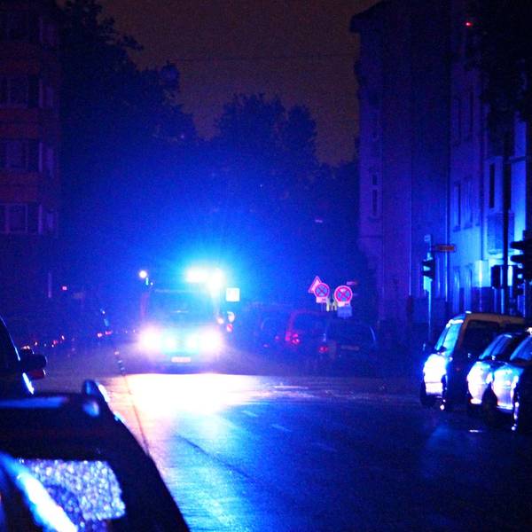 Ein Rettungswagen fährt während eines Stromausfalls mit Blaulicht durch eine dunkle Straße.