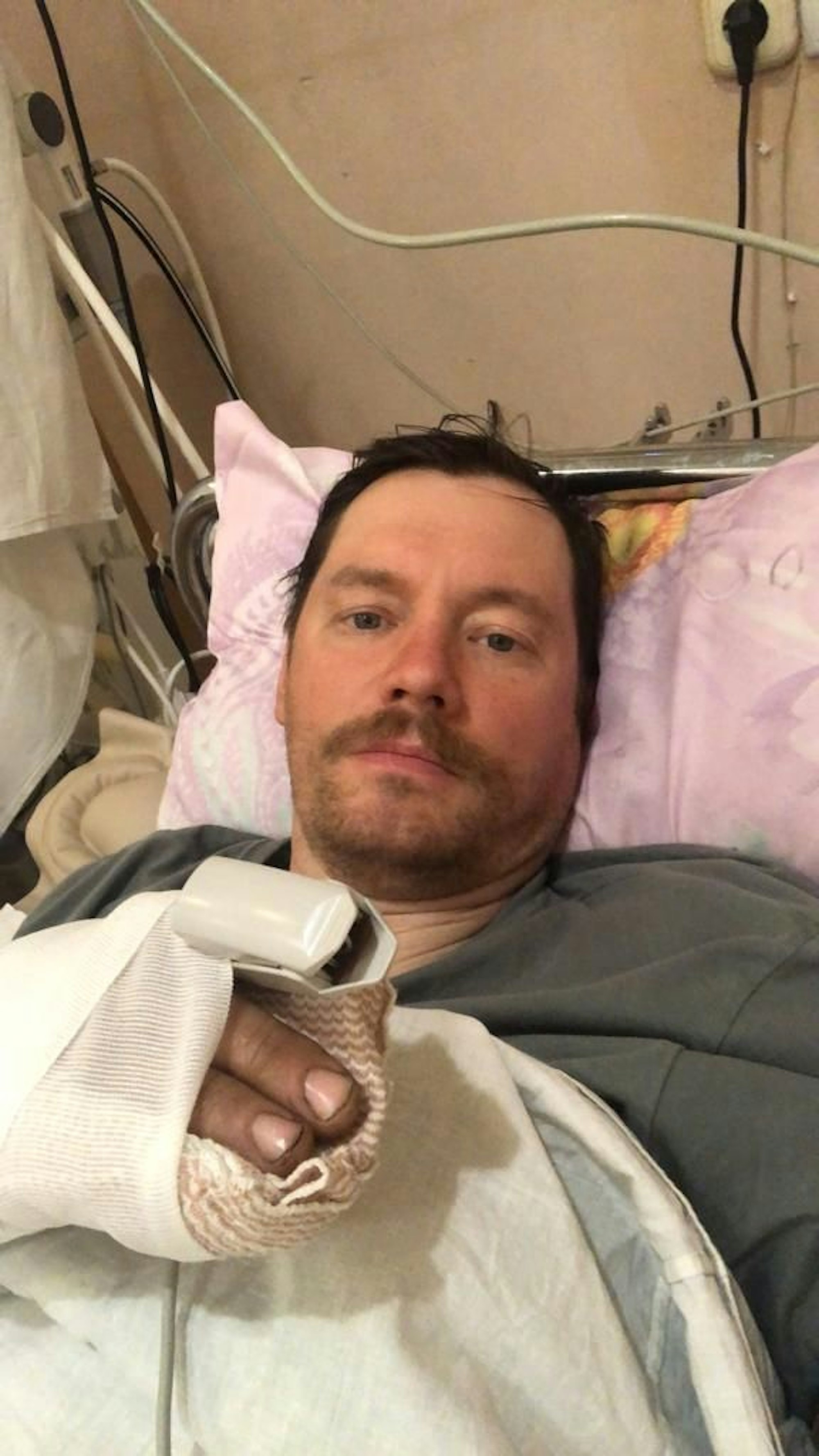 Mykola Hryhorenko liegt schwer verletzt mit verbundener Hand im Bett. Die Aufnahme ist in einem Militärkrankenhaus in der Ukraine gemacht worden.